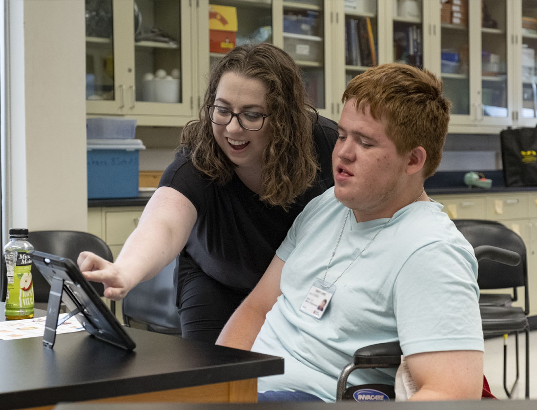 ACES student in classroom watches instructor demonstrate a tablet app