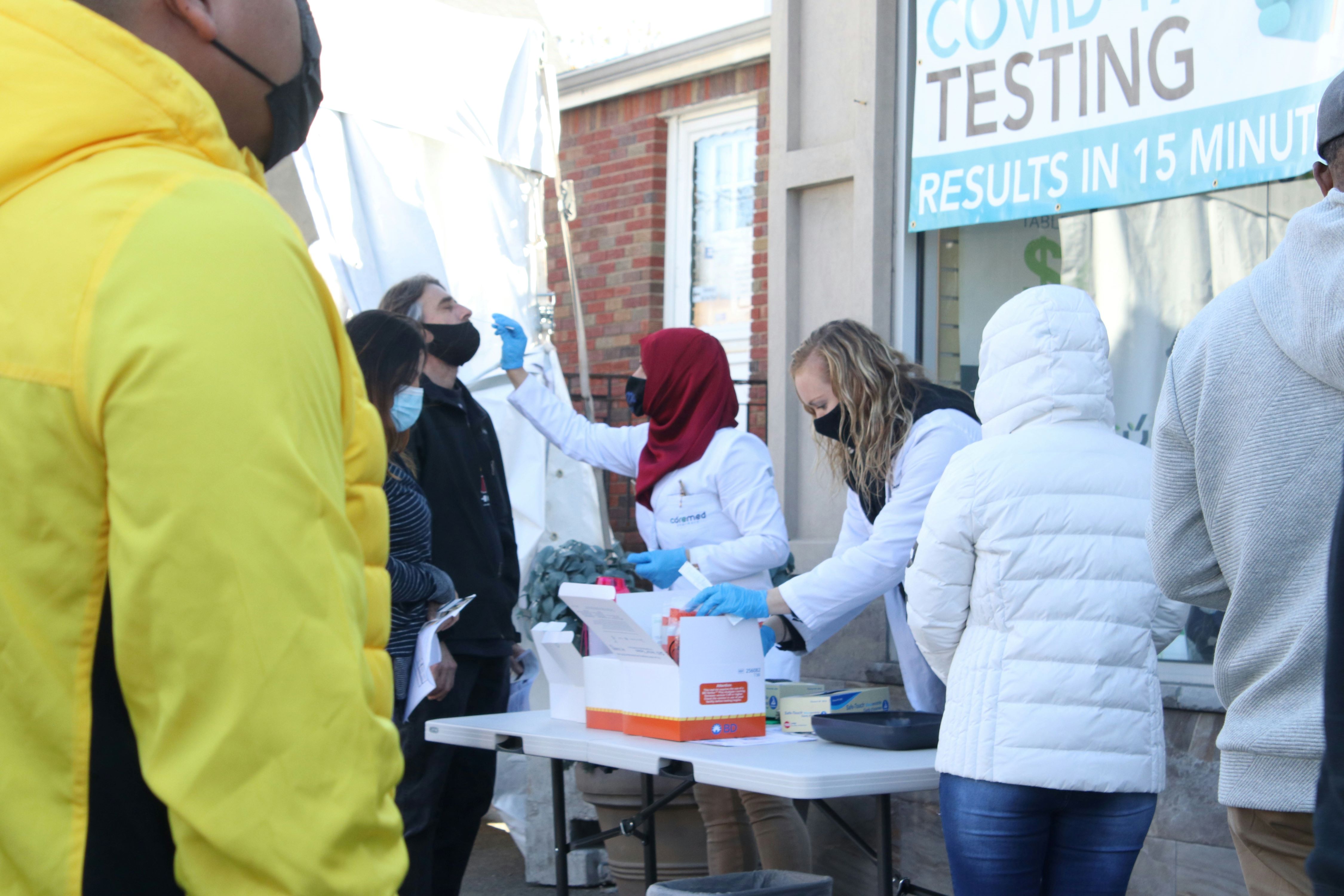 A woman administers a nasal swab at an outdoor COVID-19 testing facility