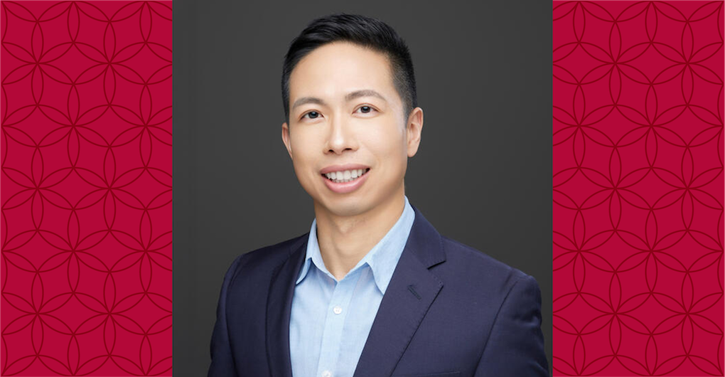 image of Steven wearing a blue suit, smiling at the camera against a red background