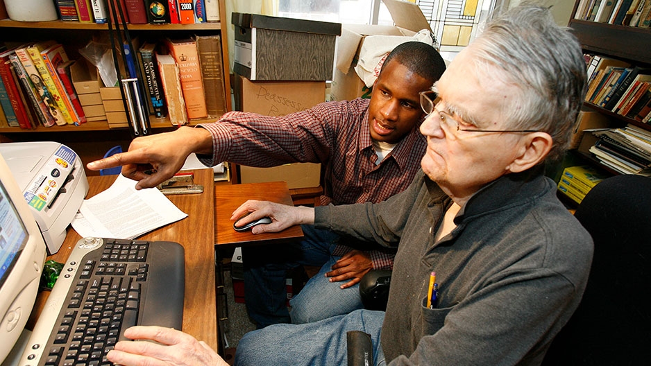 a student helping a man at a computer