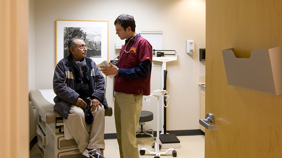 A doctor interacting with a patient inside an exam room.