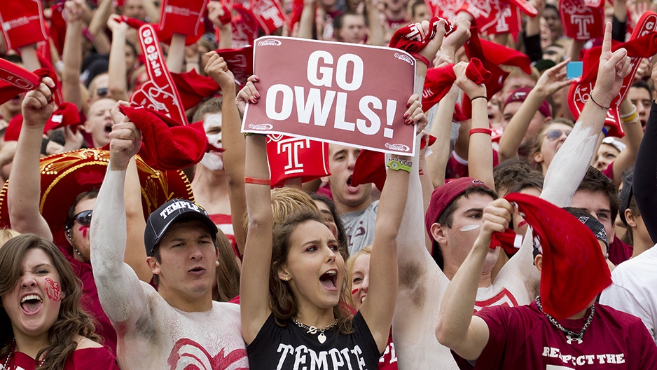 A group of students cheering at a Temple athletic event. 