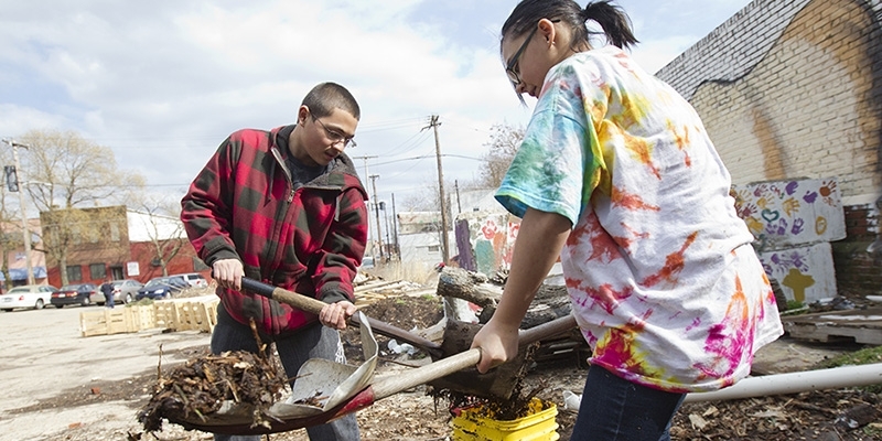 Two volunteers shoveling dirt into buckets. 