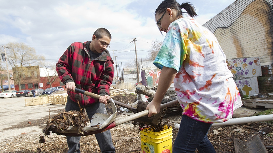 Two volunteers shoveling dirt into buckets. 