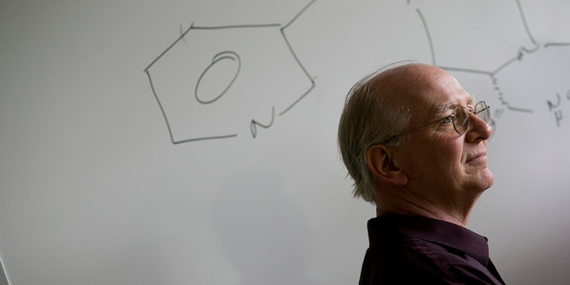 Jim Guare standing in front of a drawing of a chemical compound.