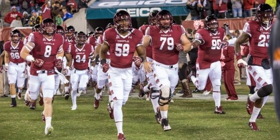 Temple football players running onto field for a game