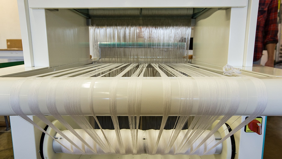 White fabric spinning on a loom.