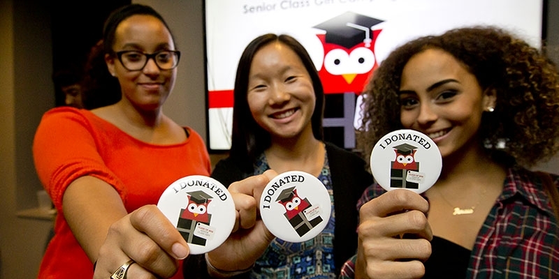 Three students each holding a sticker that says “I donated.” 