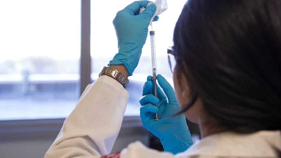 Researcher holding up a syringe
