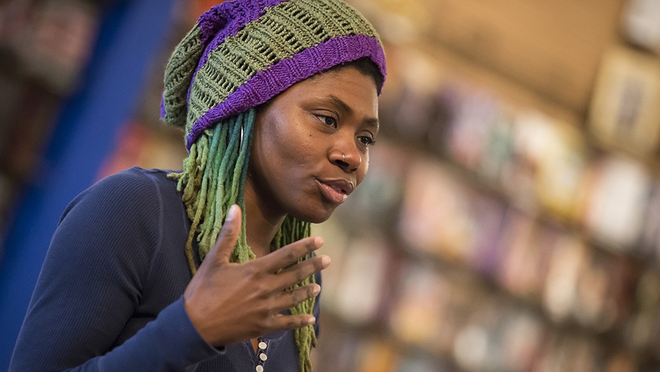 Alumna Ariell Johnson talking with comic books in the background. 