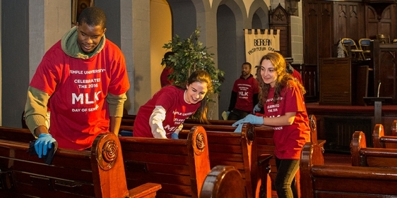 Student volunteers clean pews inside the Berean church.