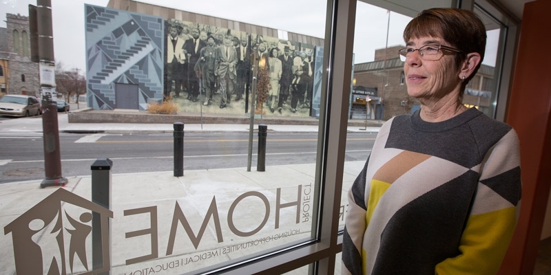 Sister Mary Scullion standing in front of a window, looking out on a mural. 