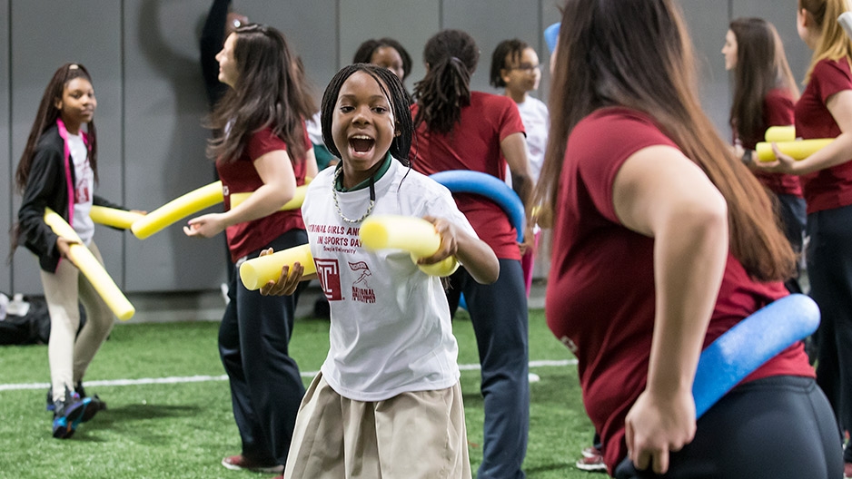 A student practicing her fencing technique with a yellow pool noodle.