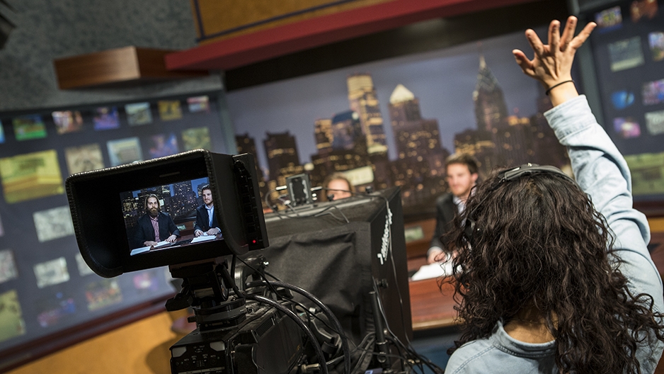 Students in a TV studio preparing to shoot a news segment.