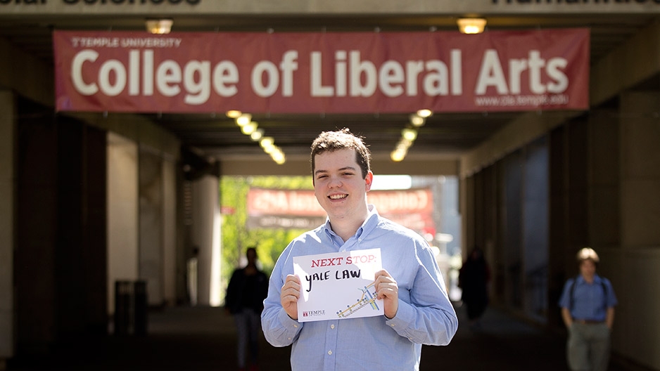  man in a blue shirt standing between two buildings on Temple’s Main Campus.