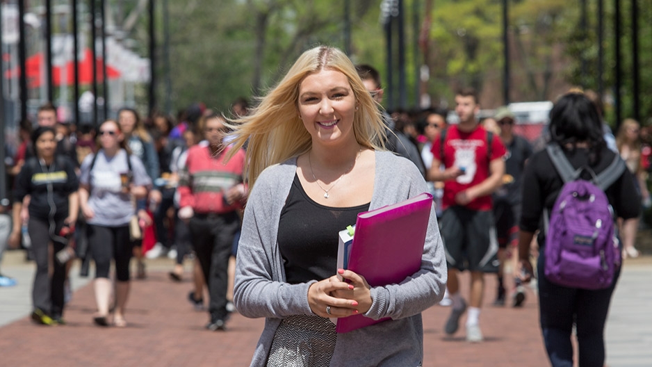 A blond woman holding books on Liacouras Walk.