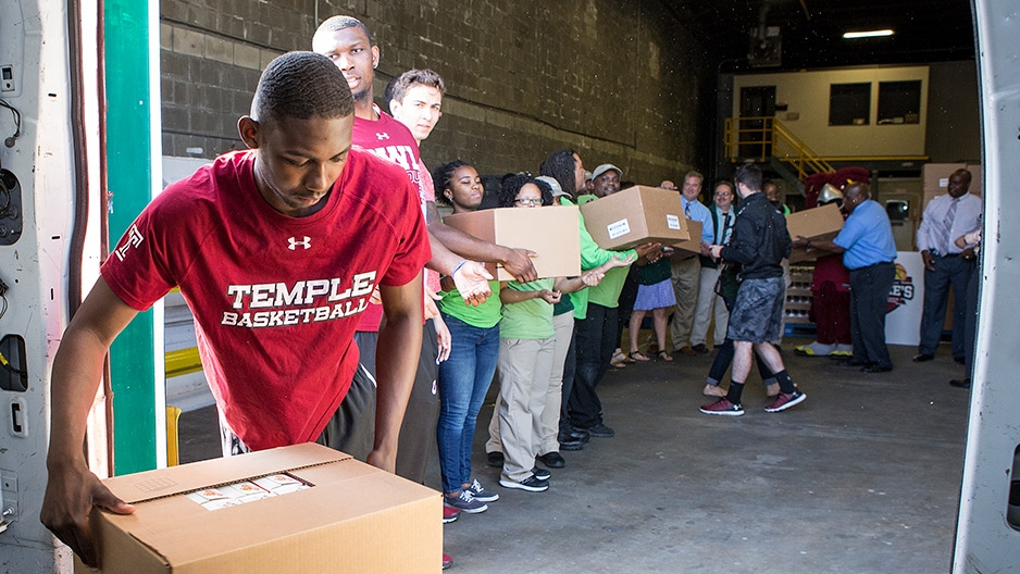 Temple men’s basketball players unloading a van at a food bank.