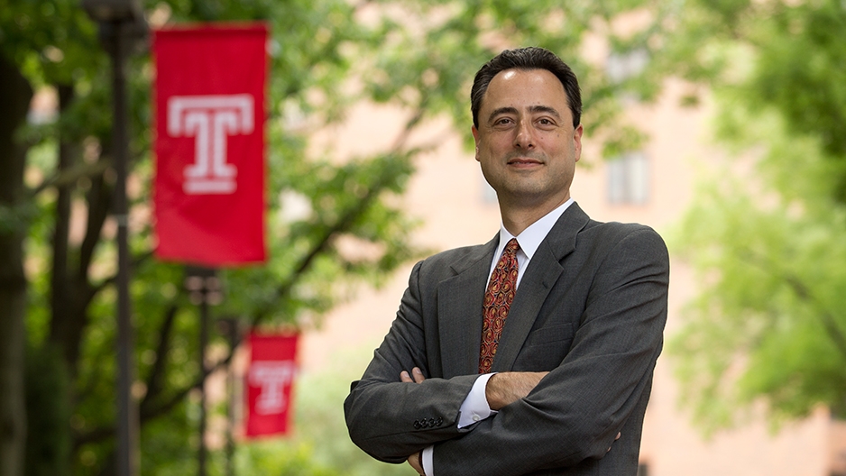 Gregory N. Mandel standing by a Temple flag.