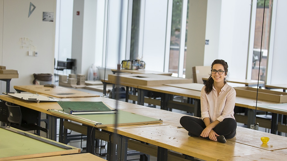 Maryam Hallaj sitting on a studio table in the architecture building.