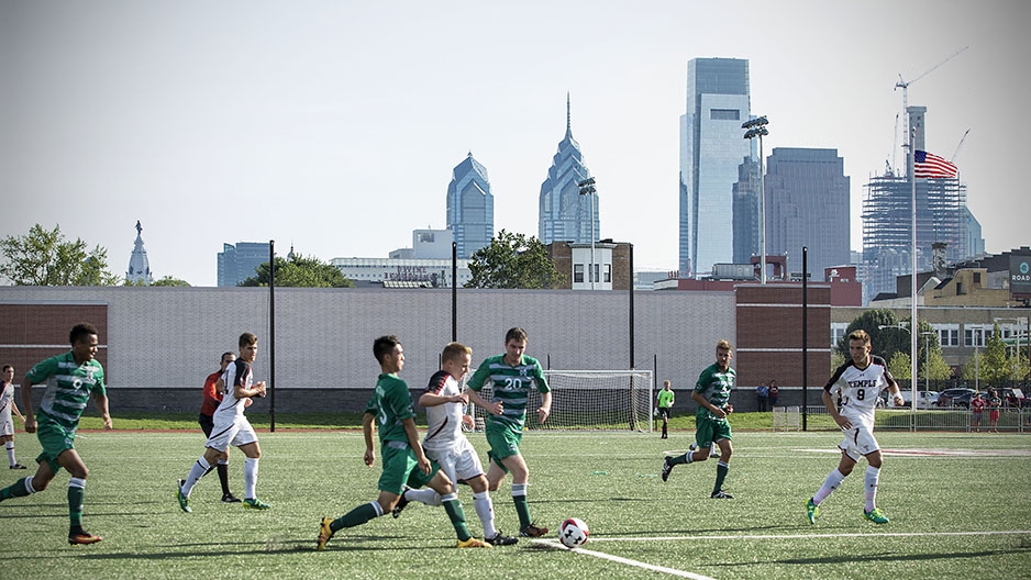 Temple men’s soccer team playing at the new sports complex with the Philadelphia skyline in the background.