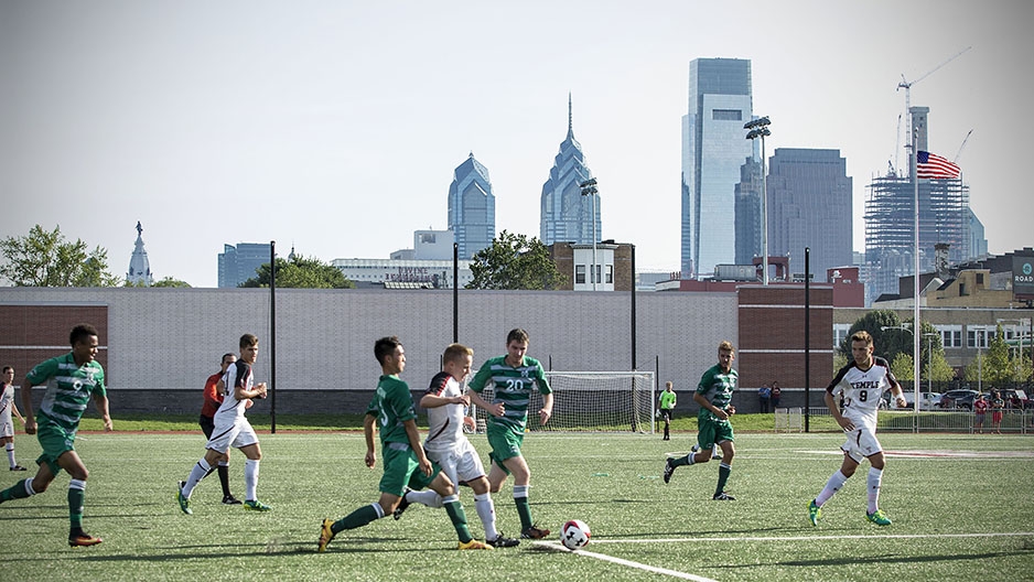 Temple men’s soccer team playing at the new sports complex with the Philadelphia skyline in the background.