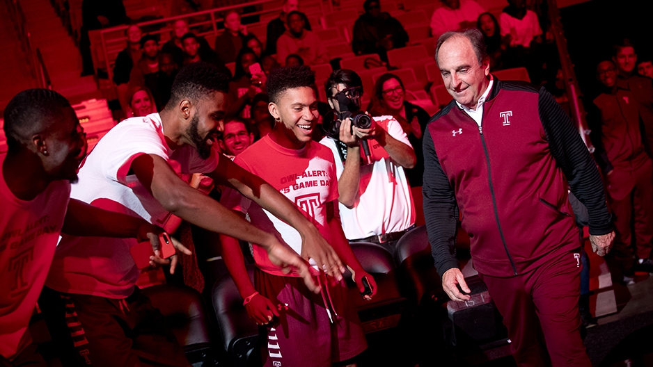 Basketball players welcoming their coach to the court.