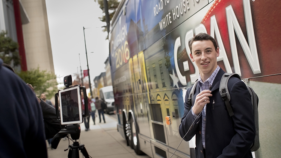 A student standing in front of the C-SPAN Bus along 13th Street.