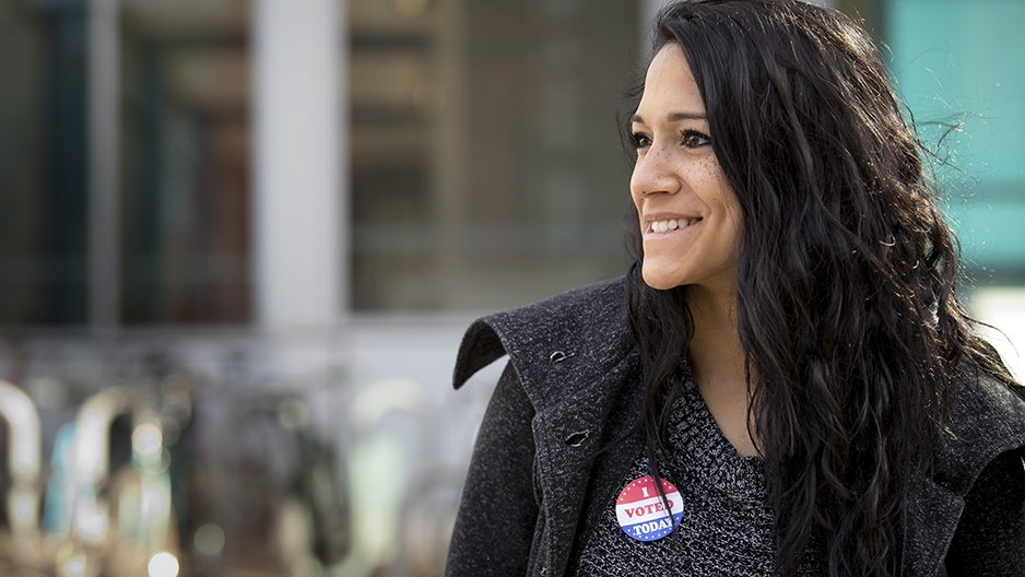 A woman smiling with an “I voted sticker” on her shirt.