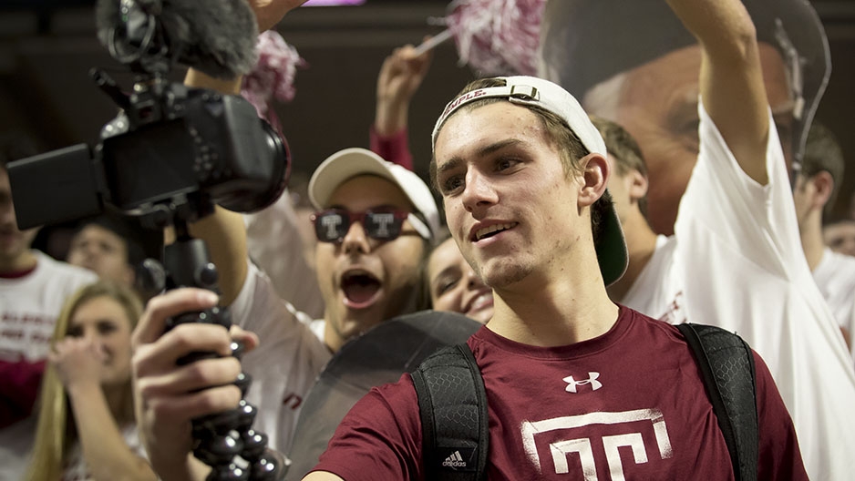 A student taking video of himself at a basketball game. 