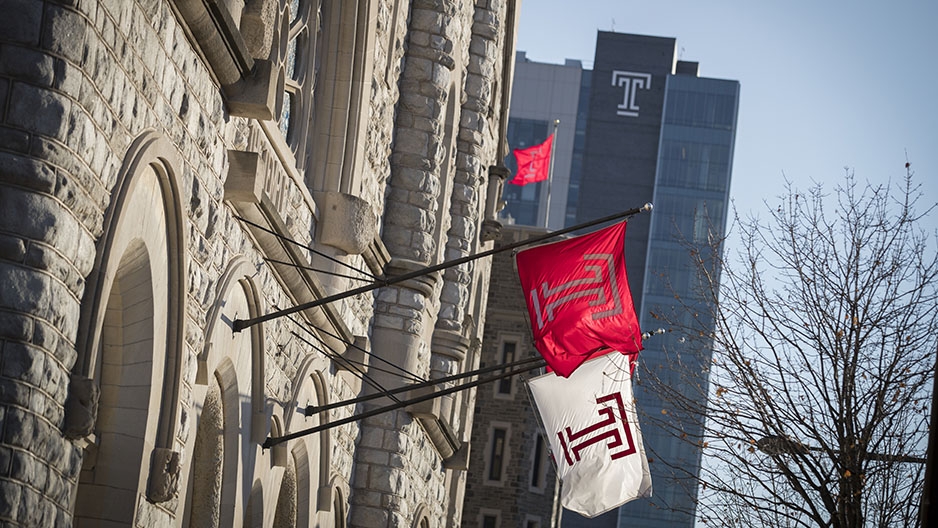 Temple flags hanging from the Temple Performing Arts Center with Morgan Hall in the background.