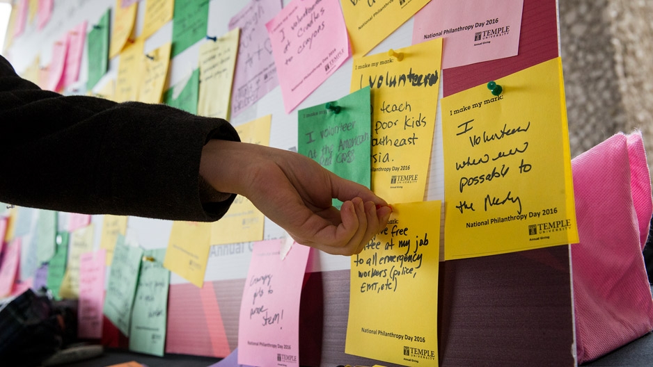 a student posting a note about giving back on a board for National Philanthropy Day.