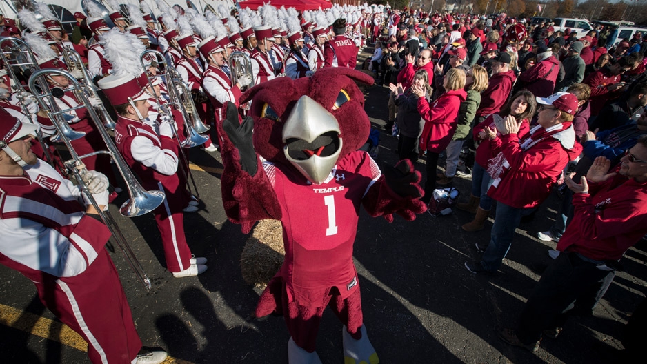 Temple mascot Hooter the Owl celebrating with the marching band and fans.