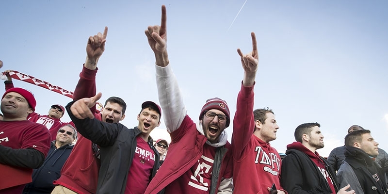 A group of students cheering at a Temple football game. 