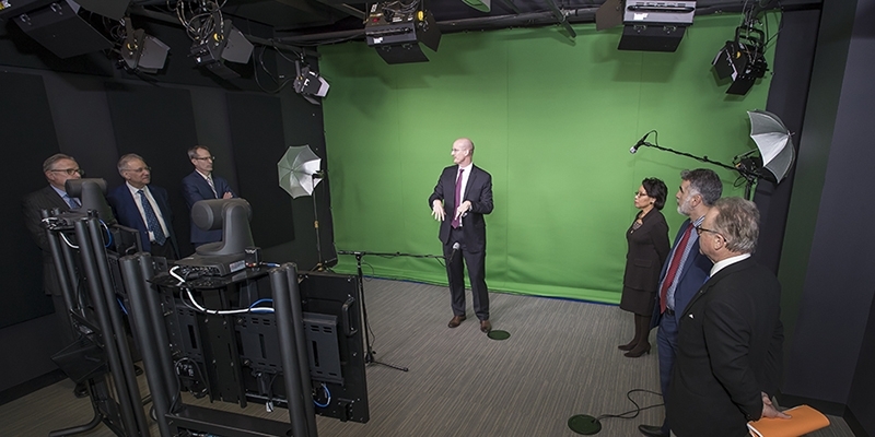 A group of administrators looking at the green screen set up in the film studio.