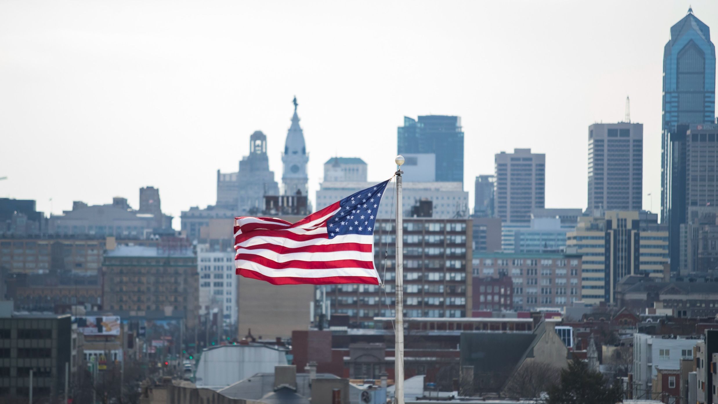 Image of an American flag in front of the Philadelphia skyline.