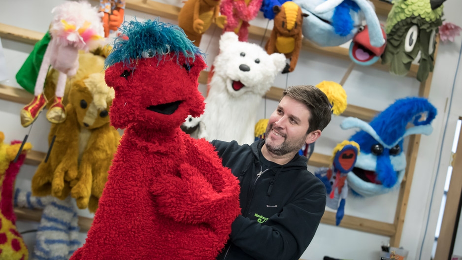 Michael Latini holding a furry red puppet.