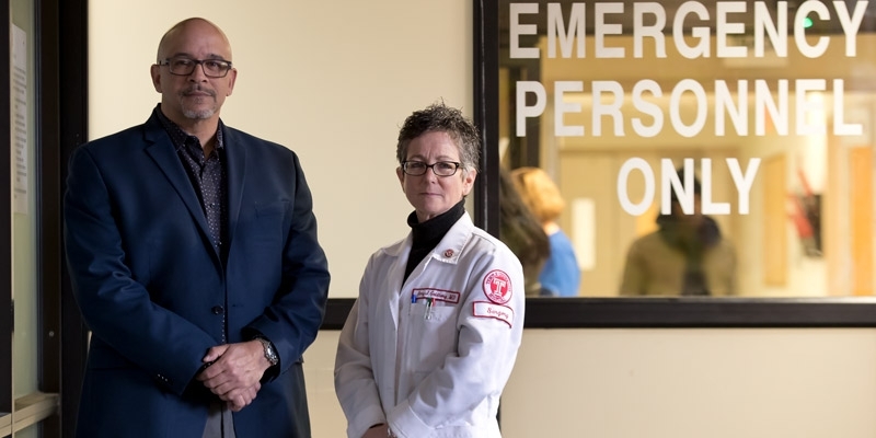 Surgeon Amy Goldberg and outreach coordinator Scott Charles standing by ER doors