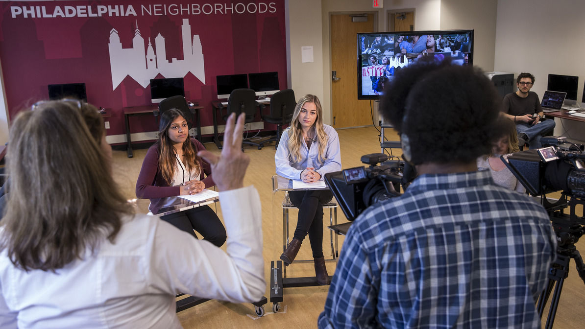 Journalism students and faculty working together in a classroom.