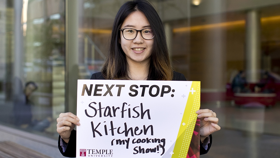 Lei Zhao holding a sign for her next stop, Starfish Kitchen.