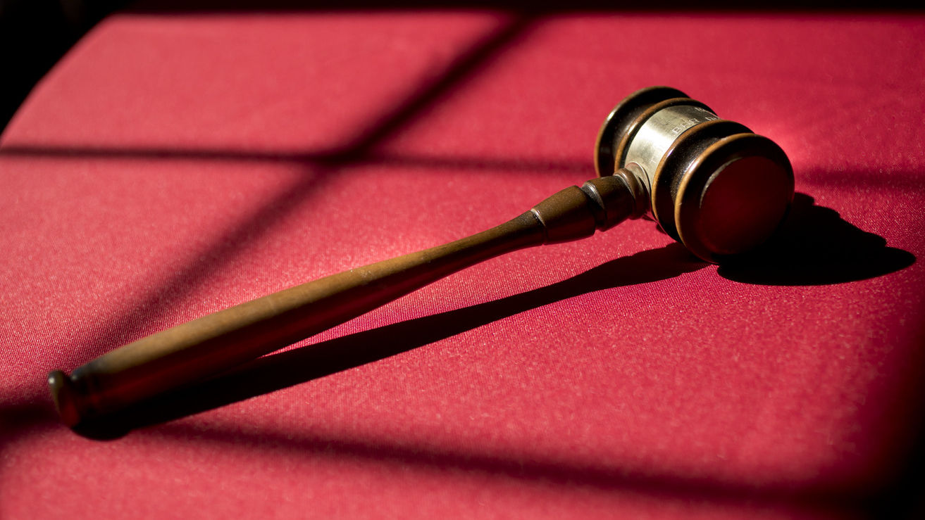 Image of a gavel placed on a table with red cloth.