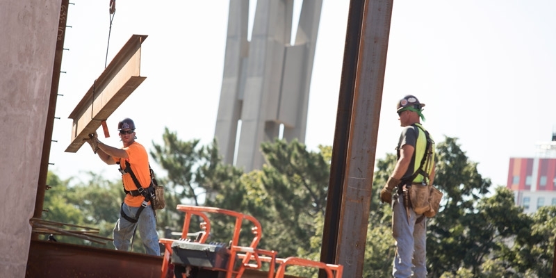 Construction workers place steel beams on Temple’s new library.