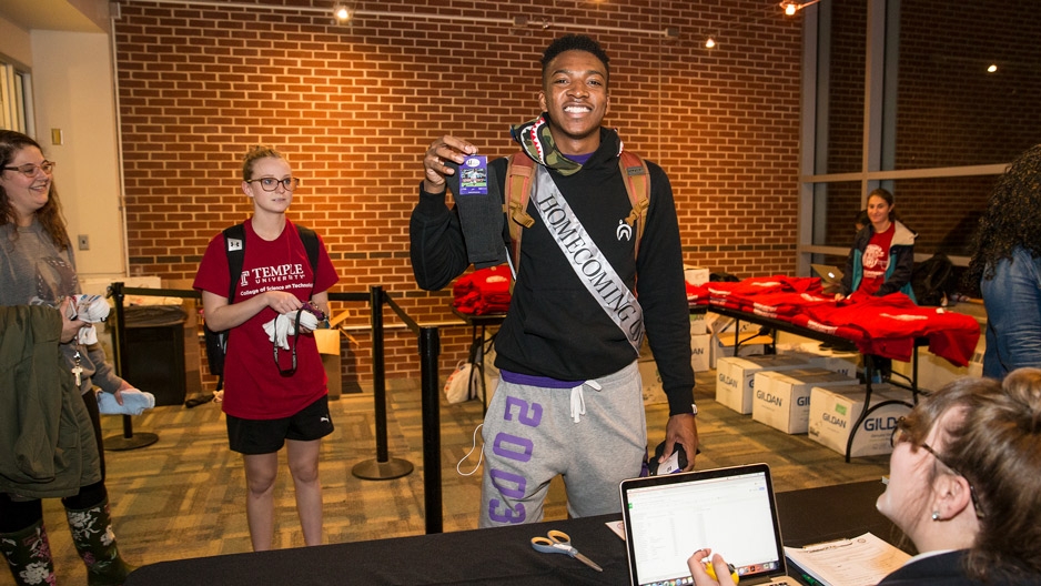 male student wearing a homecoming sash donates socks