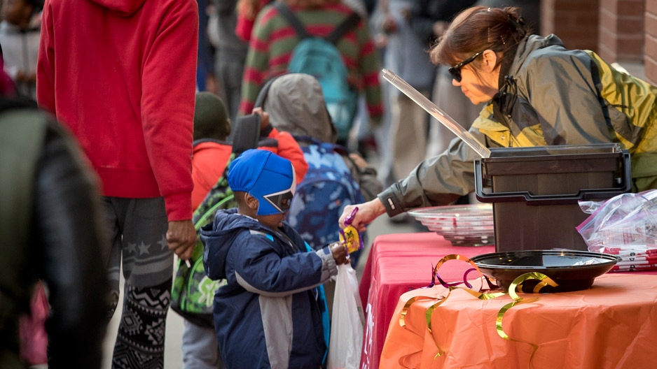 Woman handing candy to a little boy in costume during Avenue of Treats event