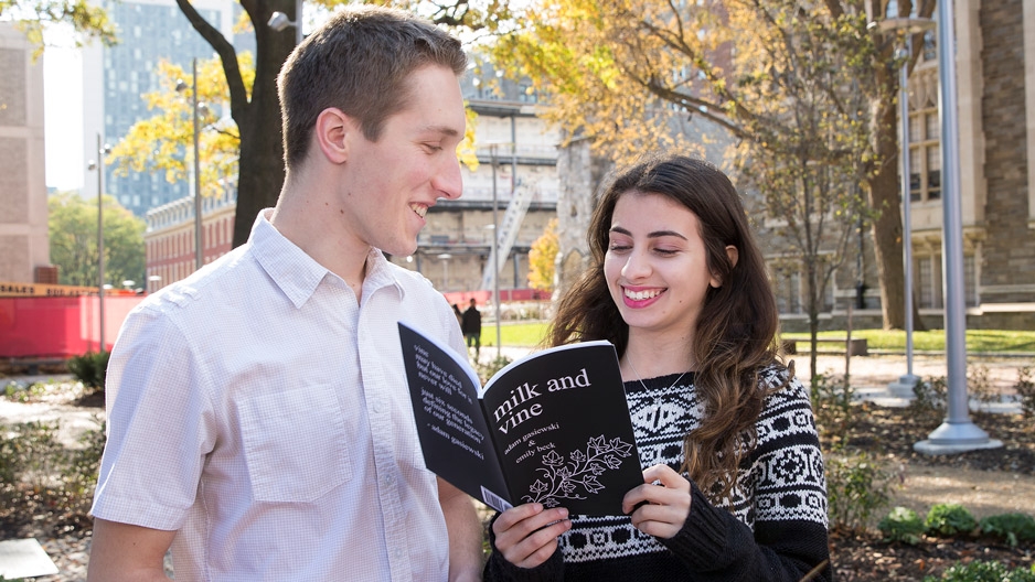 Adam Gasiewski standing with Emily Beck, who is holding a copy of Milk and Vine