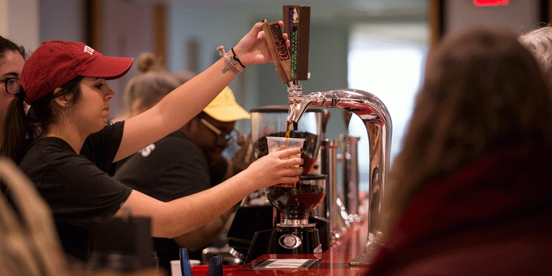A student barista pouring cold brew coffee