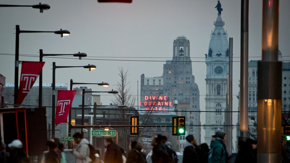 People crossing Broad Street on Temple’s campus with City Hall in the background
