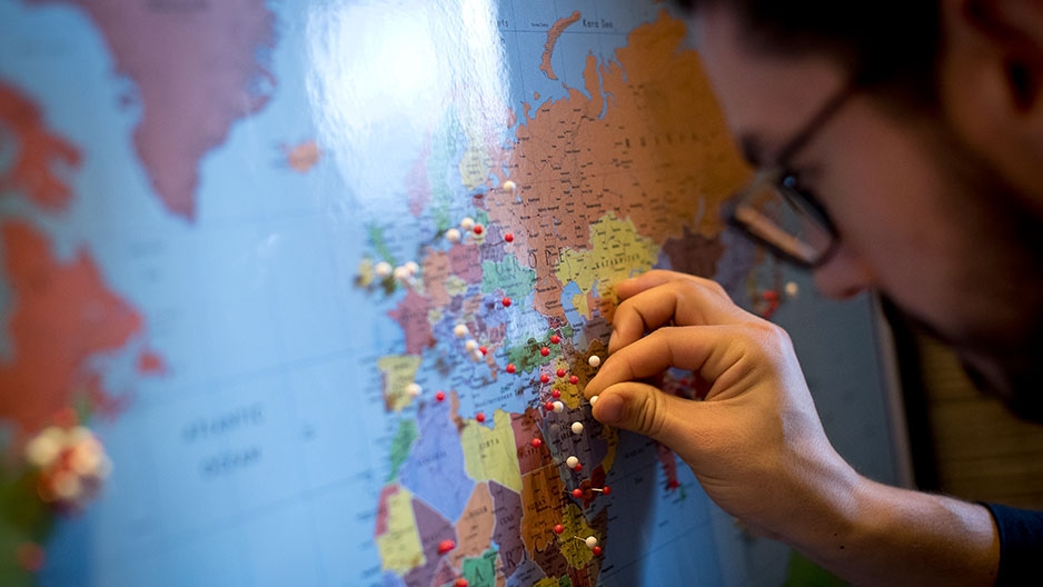 a student placing a pin on a world map