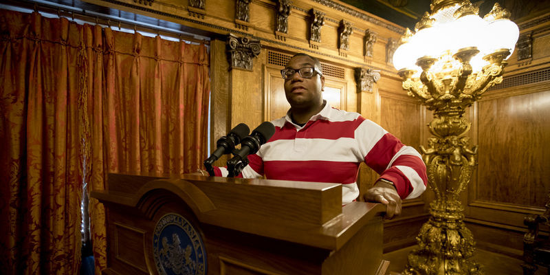 Image of Shawn Aleong behind a podium at the Pennsylvania State Capitol. 