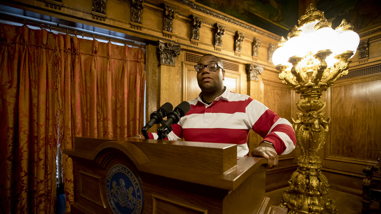 Image of Shawn Aleong behind a podium at the Pennsylvania State Capitol. 