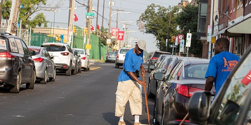 men cleaning the street near Temple's campus